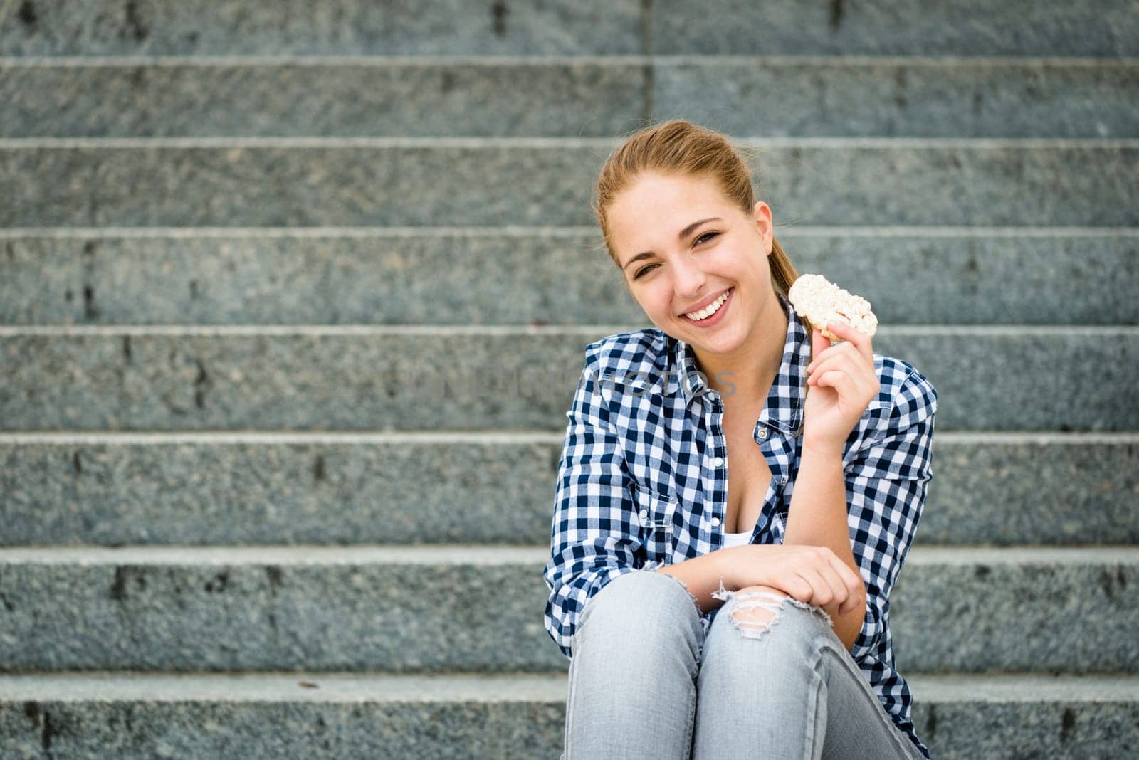 Healthy lifestyle  - teenager eating puffed bread outdoor sitting on stairs