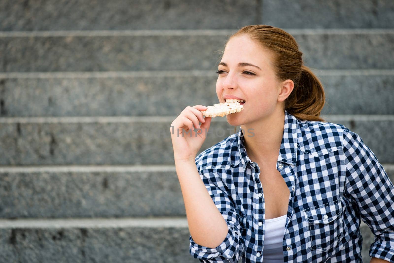 Healthy lifestyle  - teenager eating puffed bread outdoor sitting on stairs