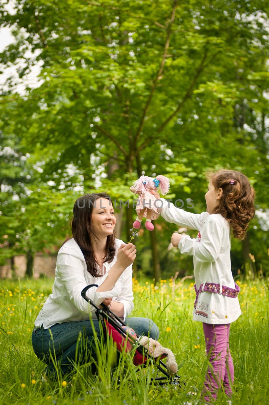 Small cute girl playing with her mother outdoors in park