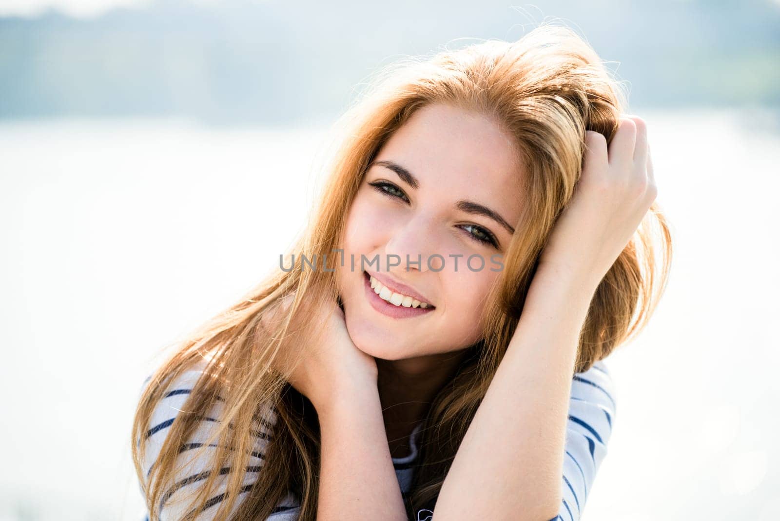 Teenager portrait - smiling girl outdoor with hands in hair
