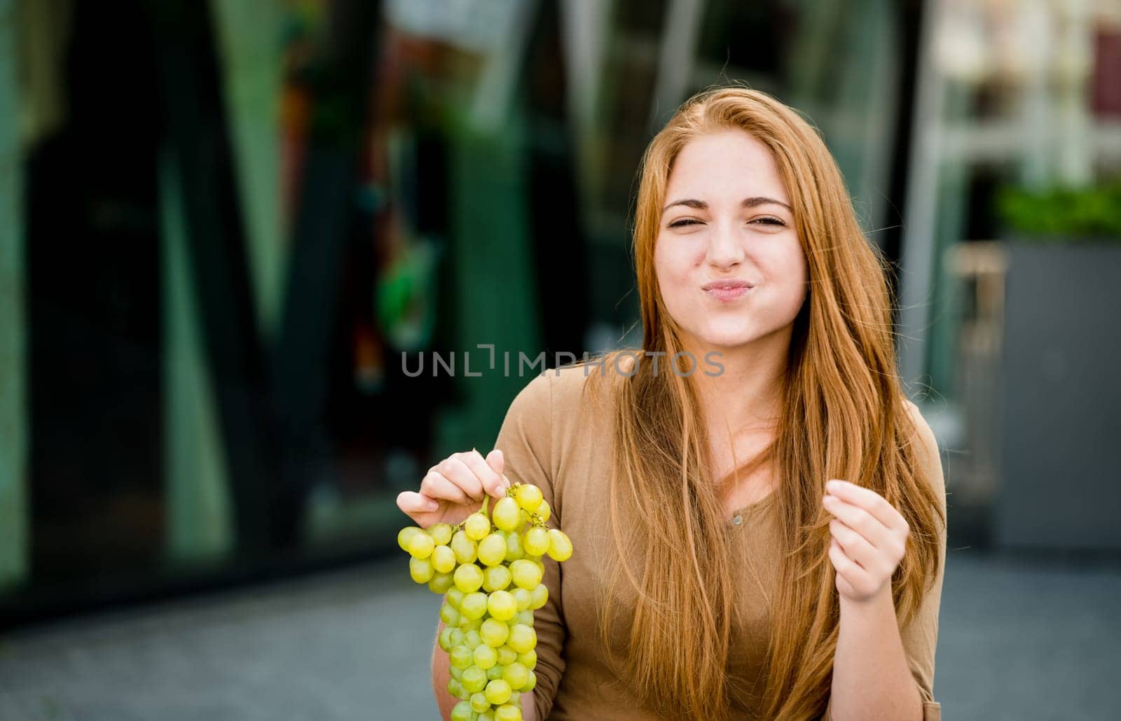 Young woman - teenage girl eating grapes outdoor in street