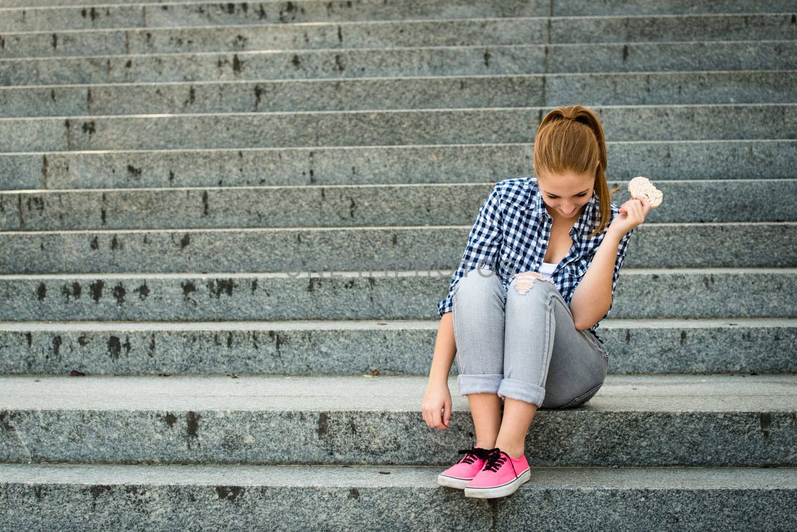 Healthy lifestyle  - teenager eating puffed bread outdoor sitting on stairs