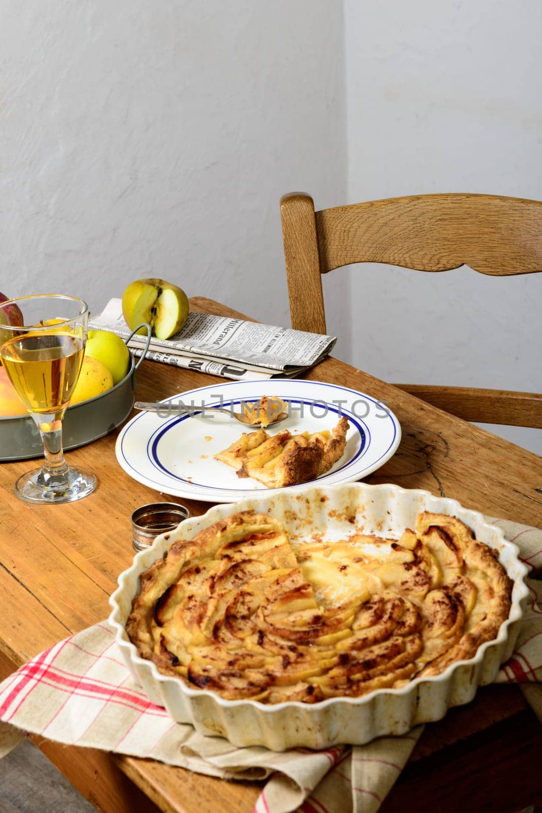 apple pie on a table with apples and glass of cider