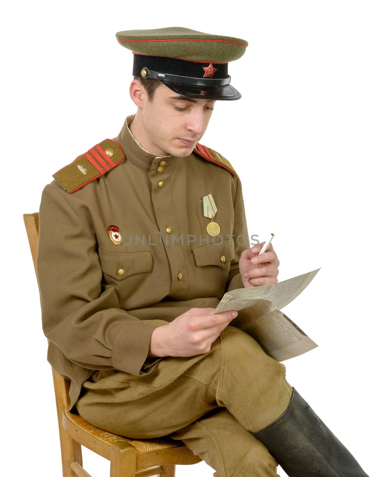 a young Soviet officer sitting in a chair read a newpaper