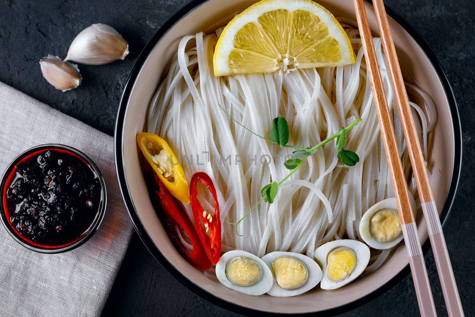 Rice noodles, Asian cuisine, with quail eggs, chili pepper and pea sprout, close-up