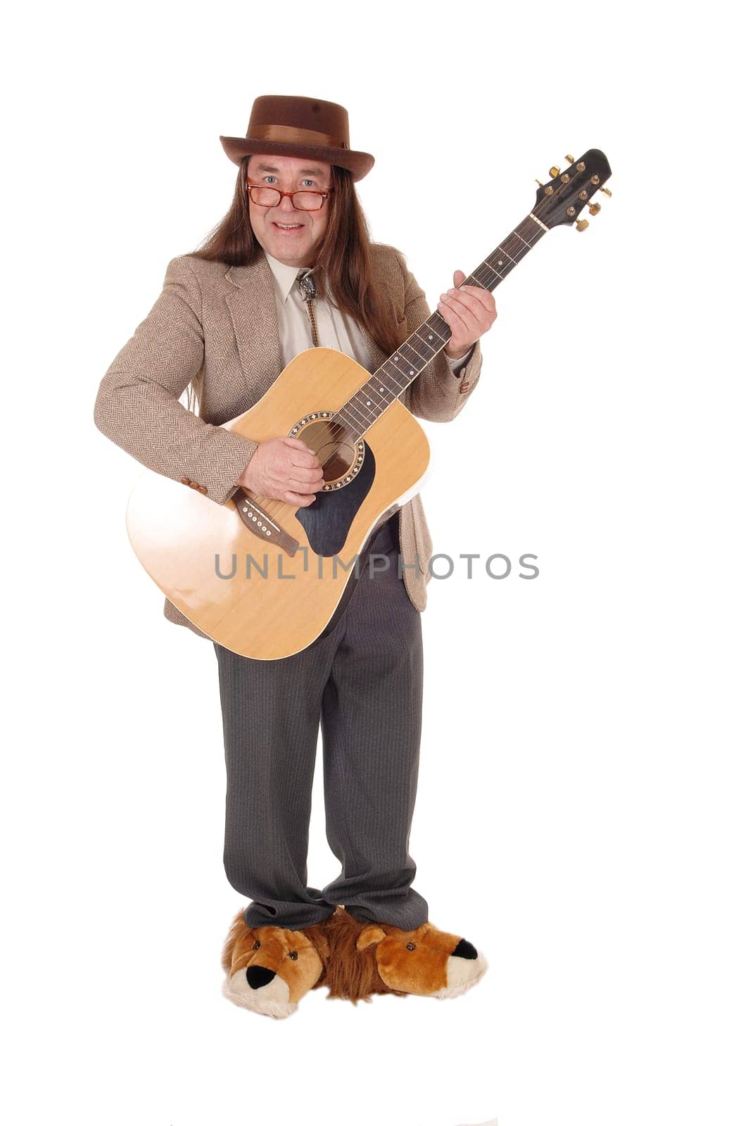 A middle age indigenous man in fancy shoes standing and playing.his guitar in a jacket and hat, isolated for white background.