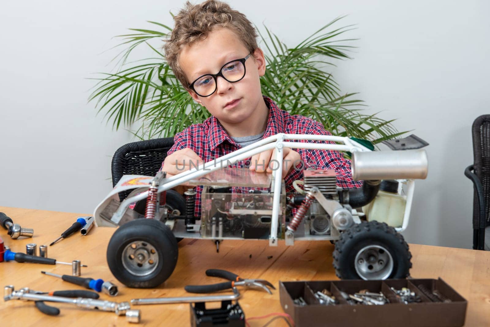 a little boy repairing a model radio-controlled car at home