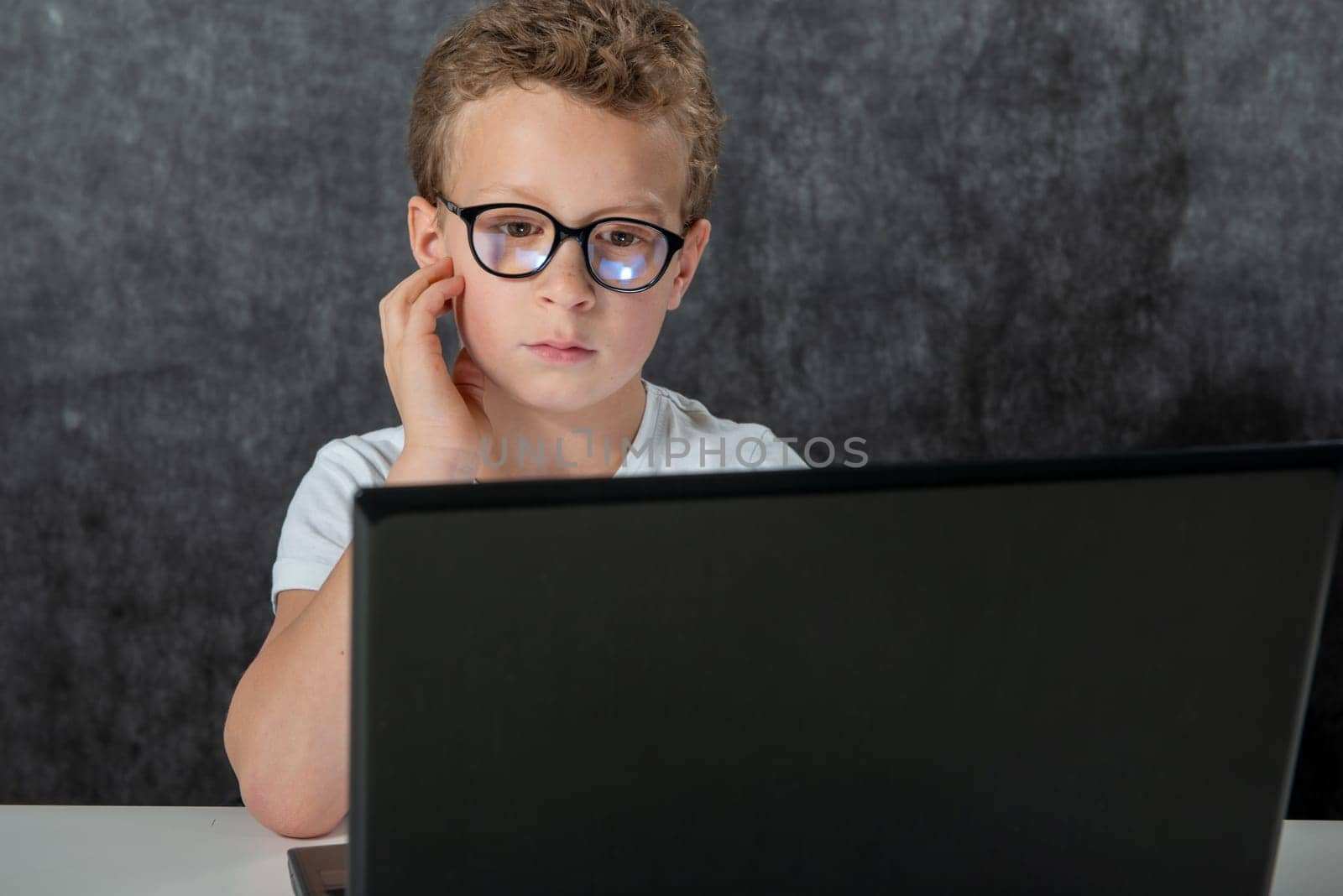 a serious boy sitting with laptop computer