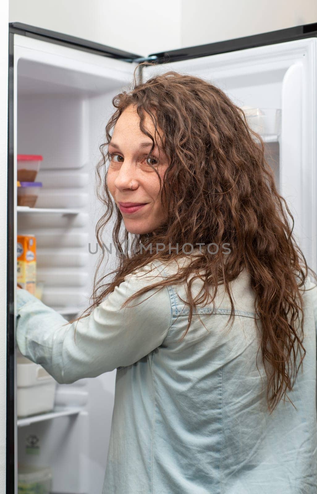 Modern attractive woman with long hair in the kitchen opening the frige door