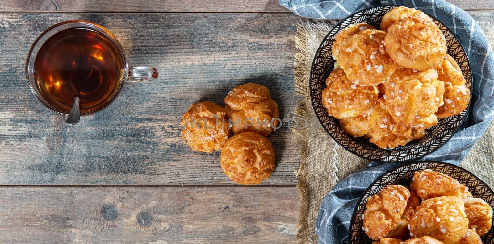 Chouquette, french choux pastry and cup of tea on the wooden table
