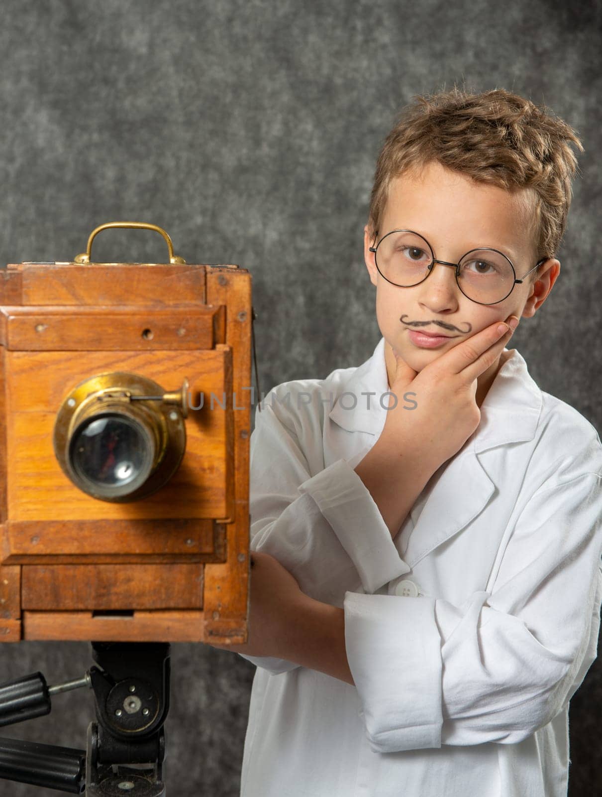 cheerful boy retro photographer with a vintage wooden camera