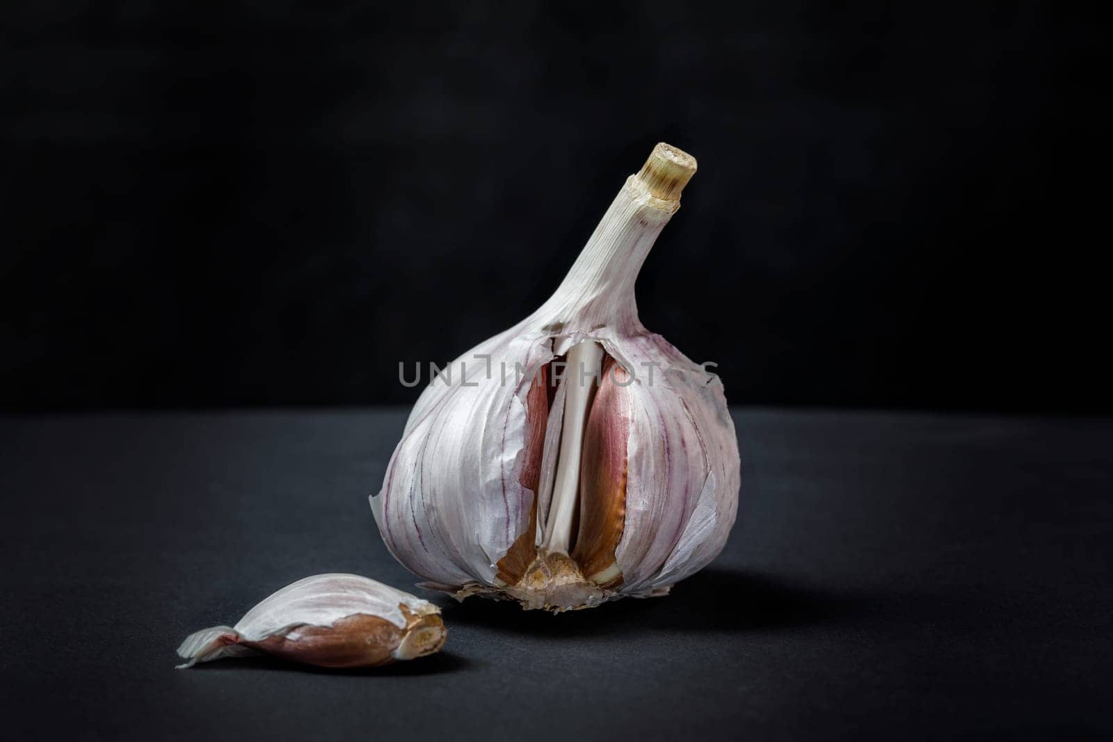 Garlic on a dark concrete background with a slice removed