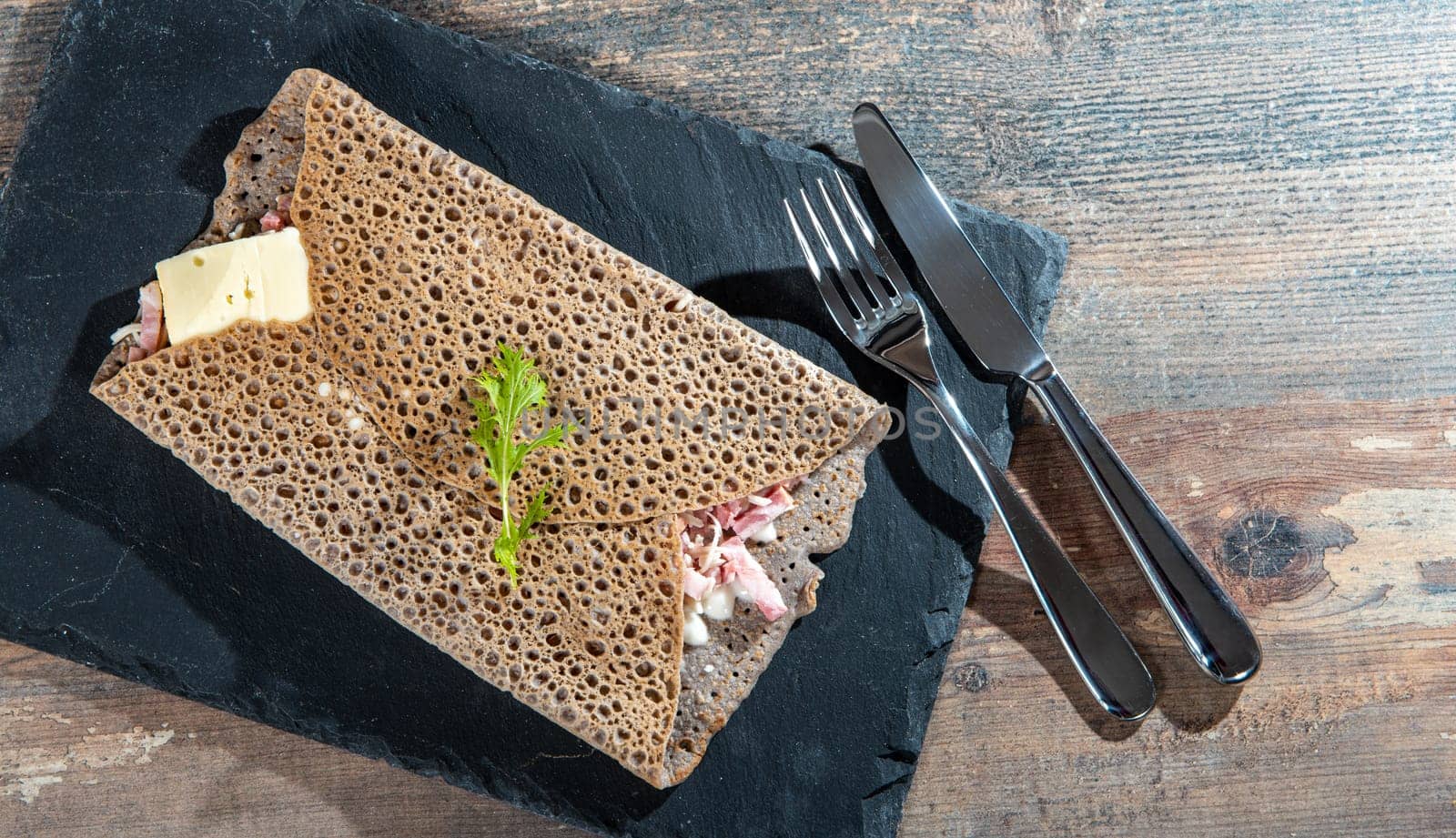 a Breton crepe with cheese and bacon on the wooden background