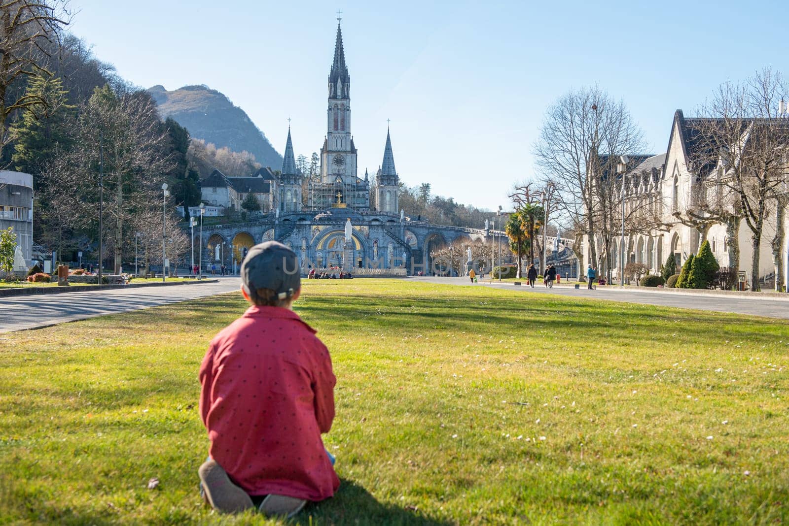 a young boy with the cathedral-sanctuary of Lourdes (France)