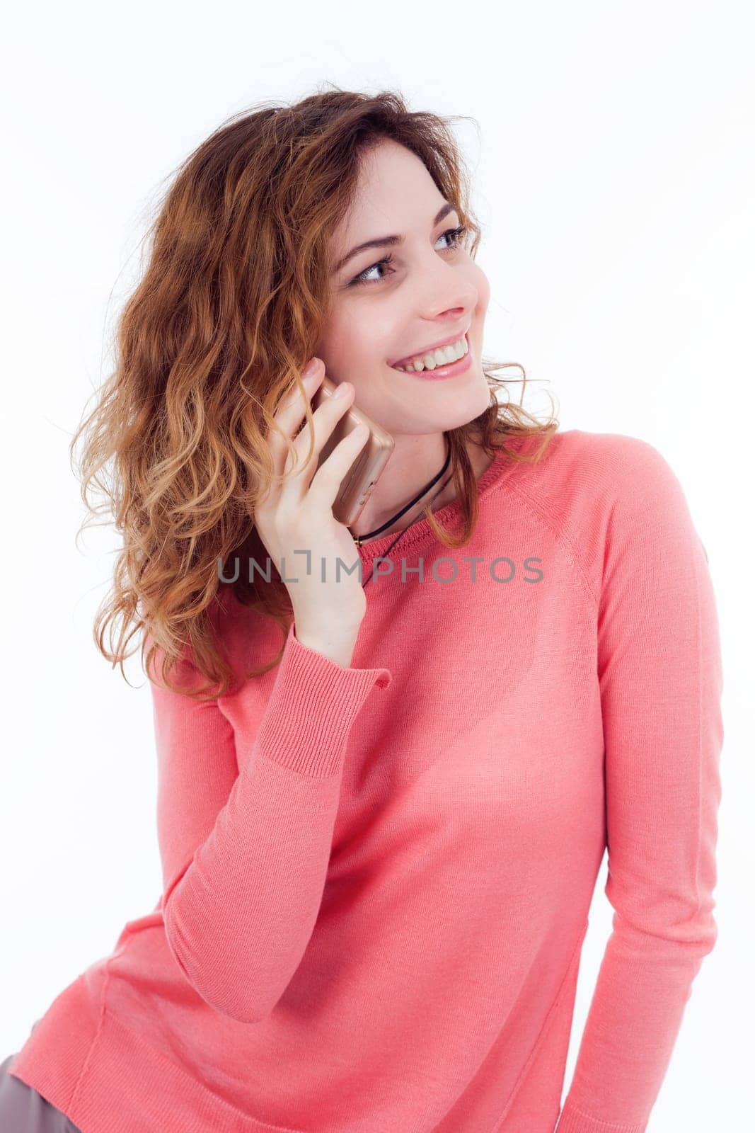 Portrait of cute joyful woman with trendy hairstyle wearing basic t-shirt talking on mobile phone isolated over white background.