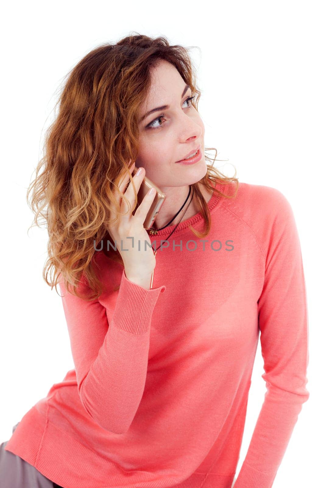 Portrait of cute joyful woman with trendy hairstyle wearing basic t-shirt talking on mobile phone isolated over white background.