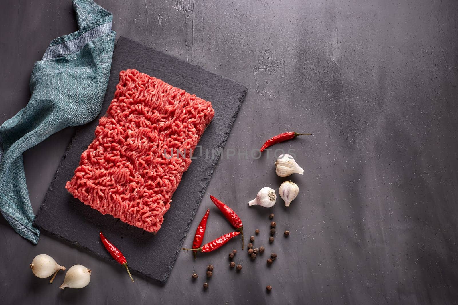 Still life with fresh forcemeat from beef and spices on a dark background. Top view with copy space