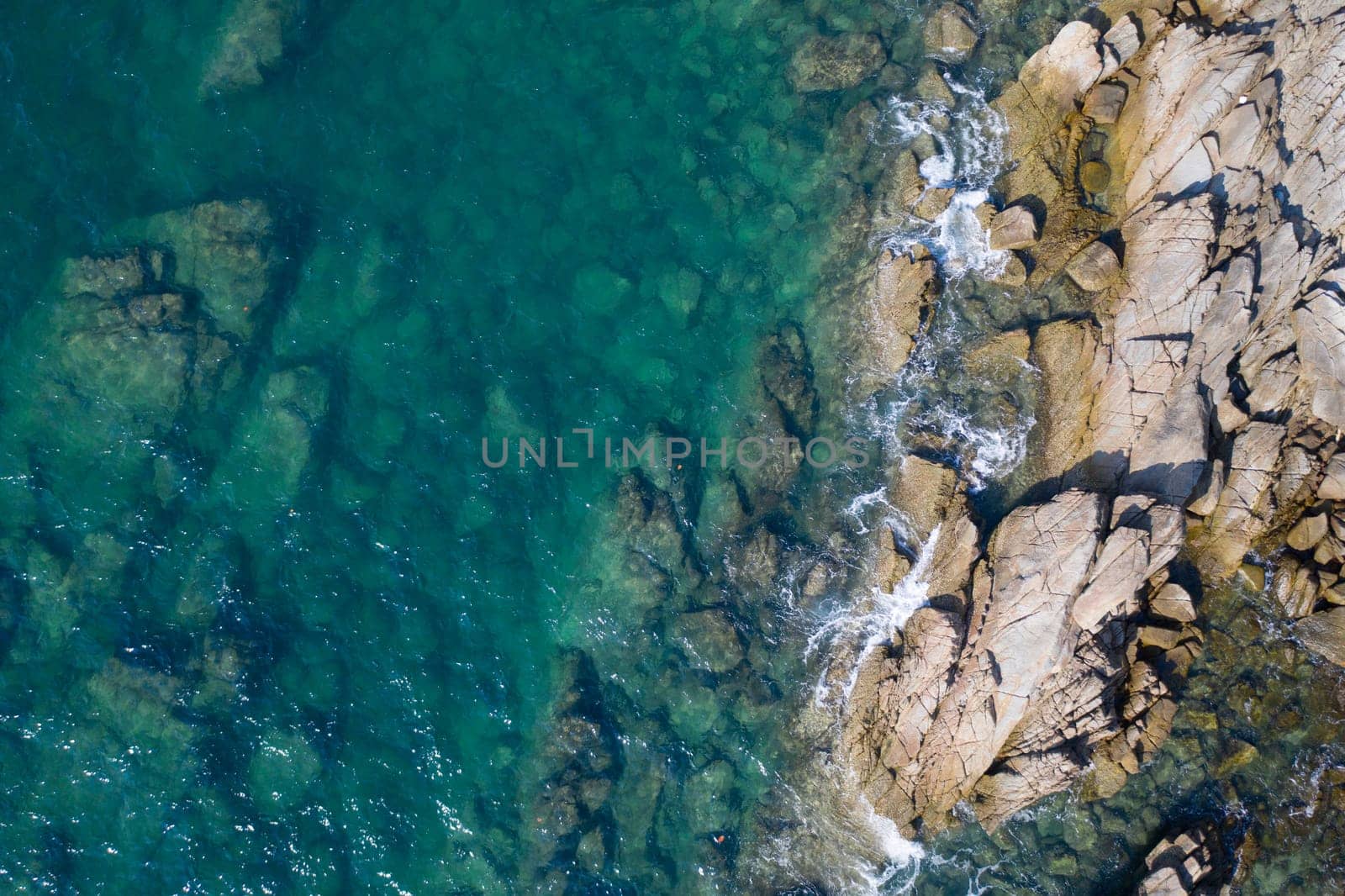 Aerial drone top view of turquoise sea surface with stones and rocks in water