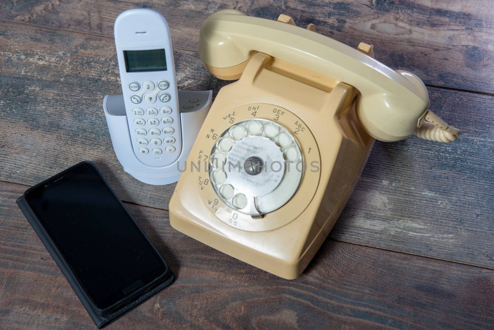 Old retro phone and new cell phone on wooden board