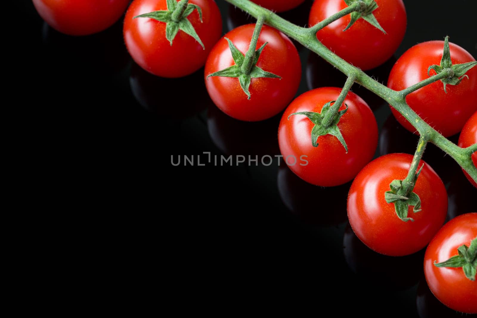 Fresh cherry tomatoes on a black background. Bunch of fresh cherry tomato on a black background