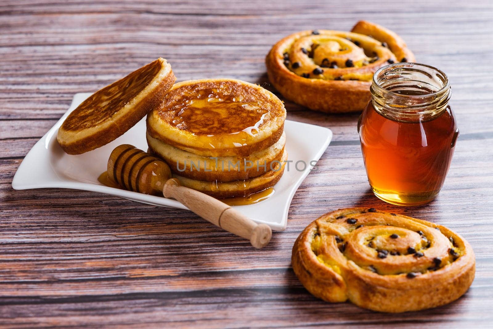 Pancakes with liquid honey on wooden background.