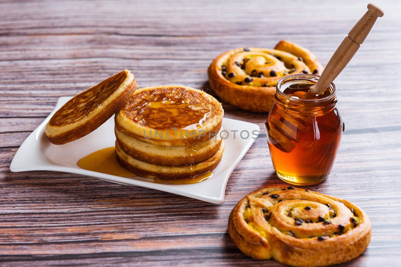 Pancakes with liquid honey on wooden background.