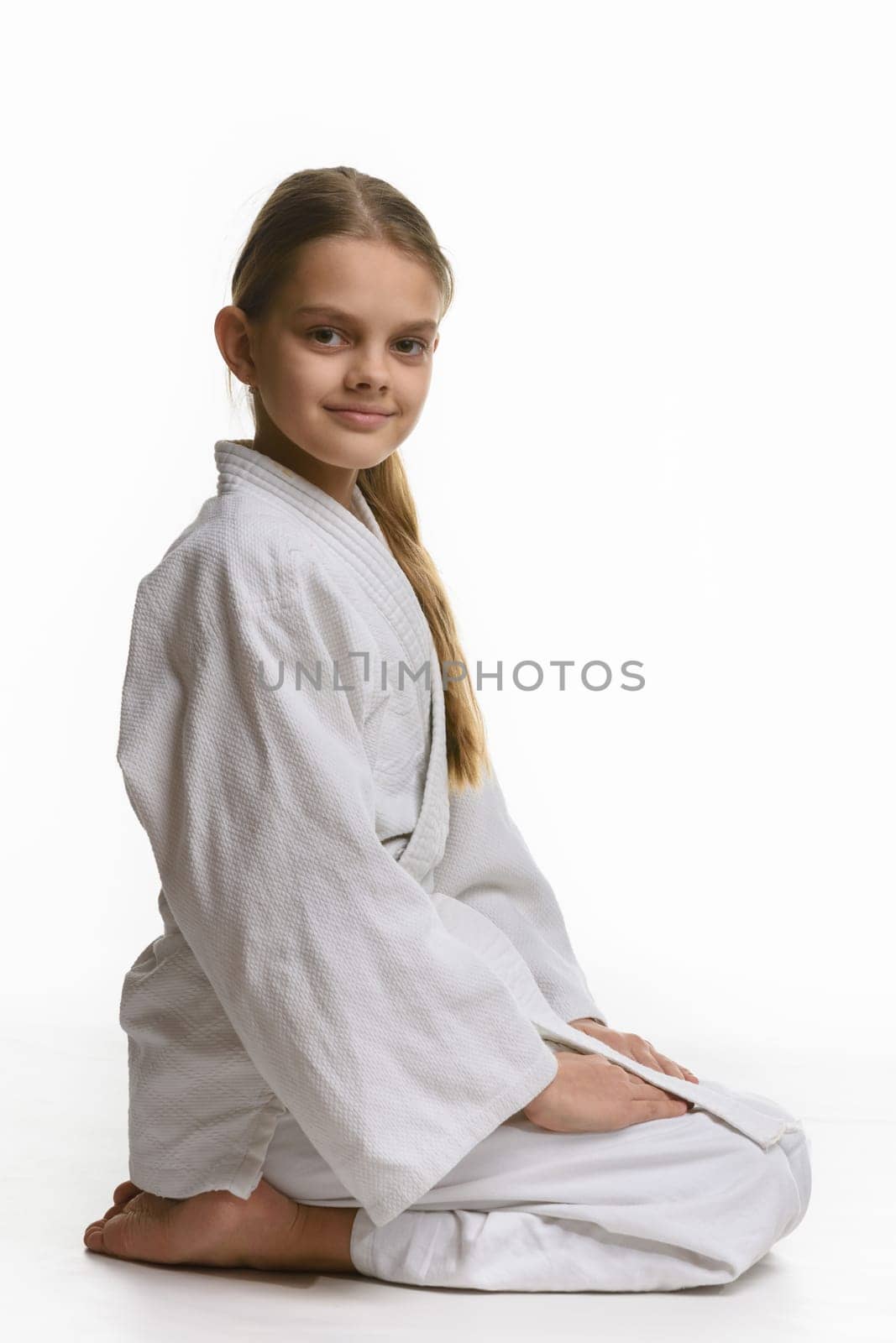 Girl in judo class, sitting on the floor, the view from the side
