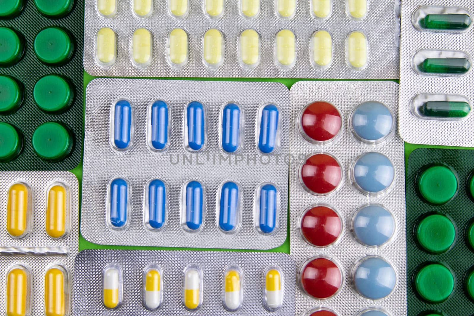 Pills of different colours lay on blue background. Colorful antibacterials pills, capsules of medicine.