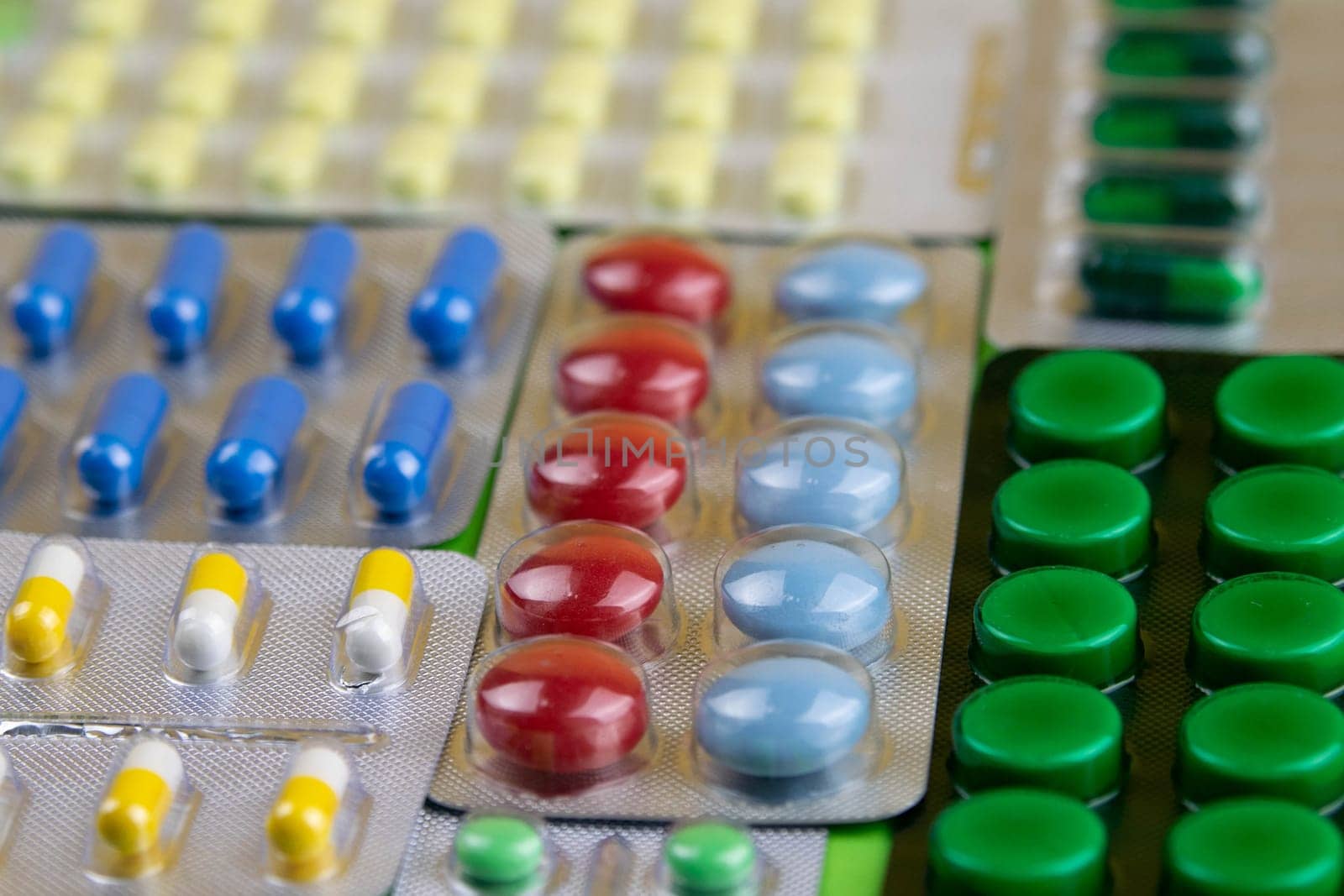 Pills of different colours lay on blue background. Colorful antibacterials pills, capsules of medicine.