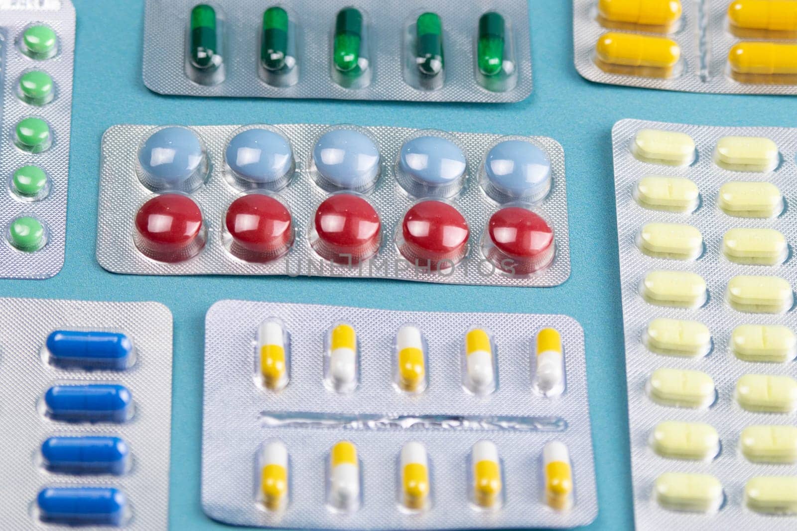 Pills of different colours lay on blue background. Colorful antibacterials pills, capsules of medicine.