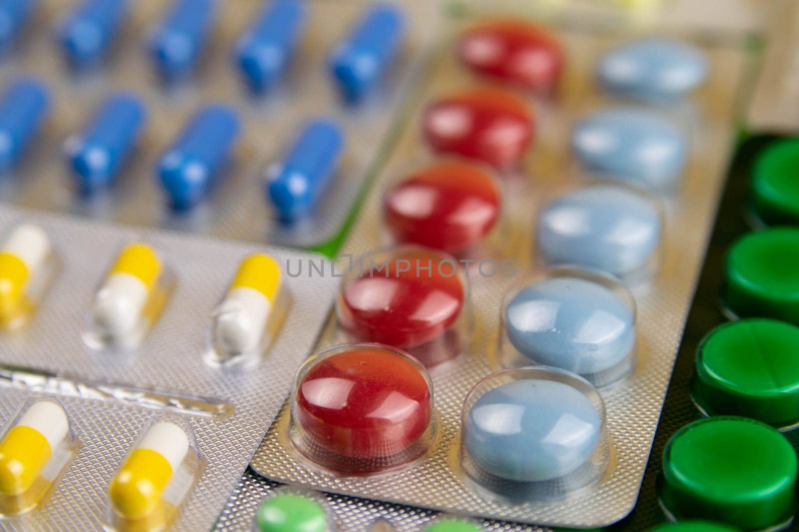 Pills of different colours lay on blue background. Colorful antibacterials pills, capsules of medicine.