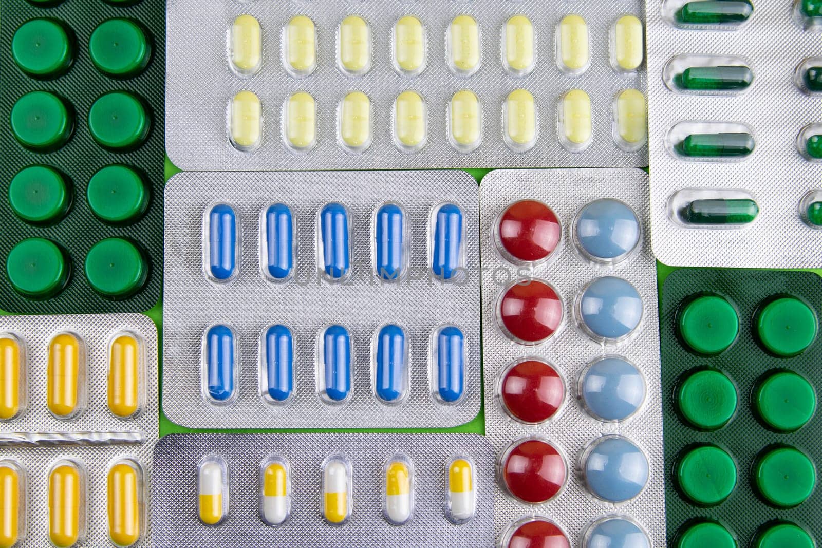 Pills of different colours lay on blue background. Colorful antibacterials pills, capsules of medicine.