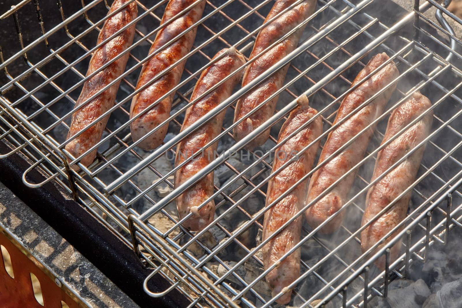 Pork sausages.  Cooking on barbecue grill ( chargrill, brazier). Top view, closeup. Outdoors. Fast food