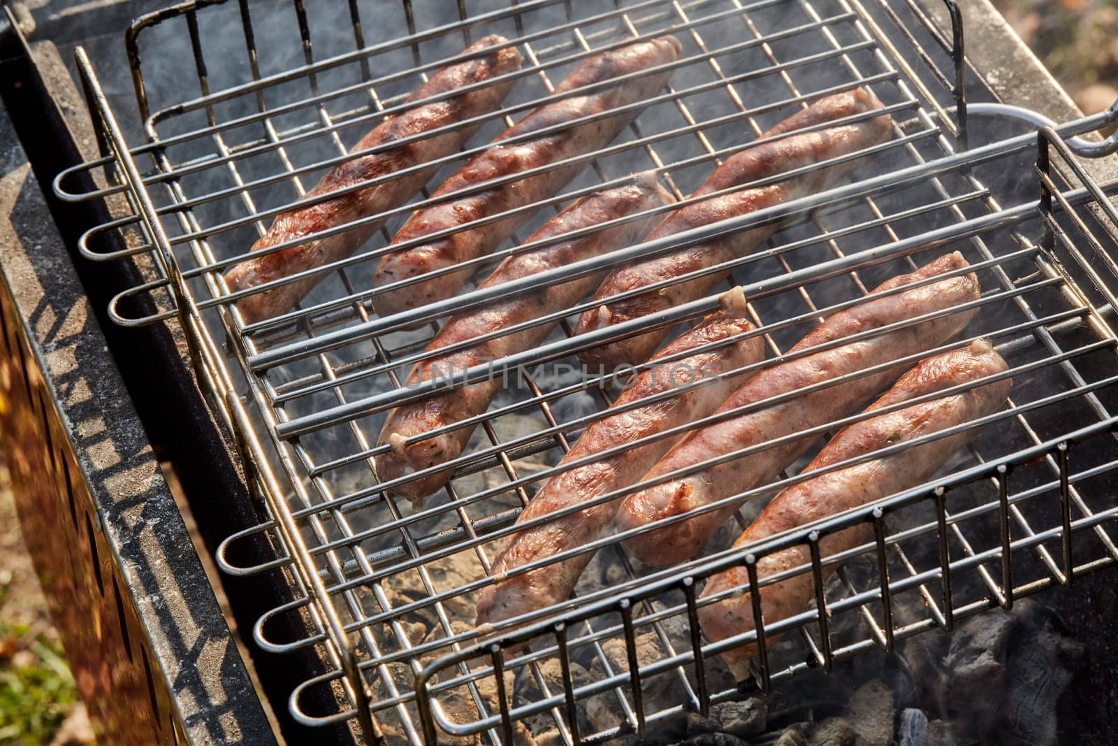 Pork sausages.  Cooking on barbecue grill ( chargrill, brazier). Top view, closeup. Outdoors. Fast food