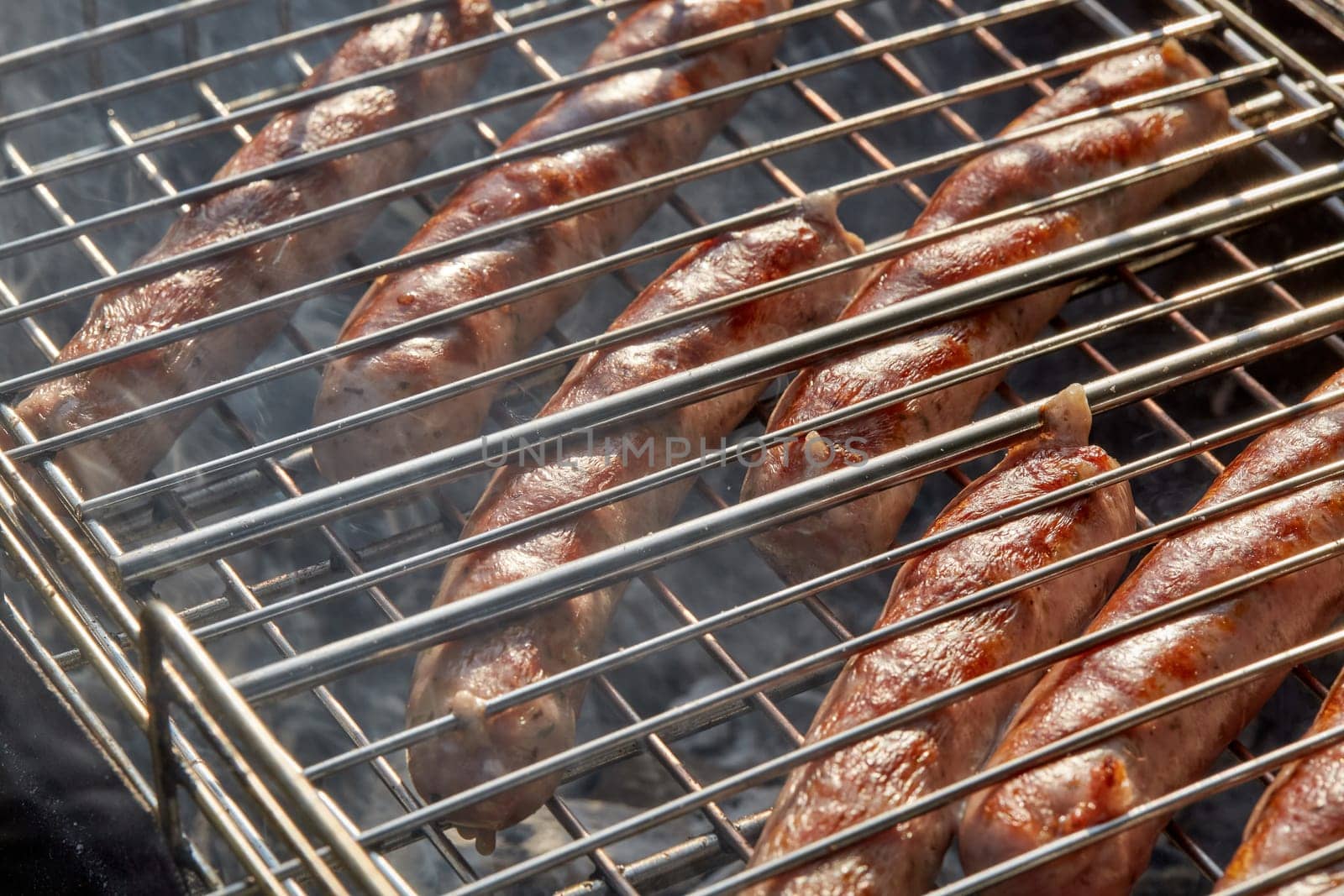 Pork sausages.  Cooking on barbecue grill ( chargrill, brazier). Top view, closeup. Outdoors. Fast food