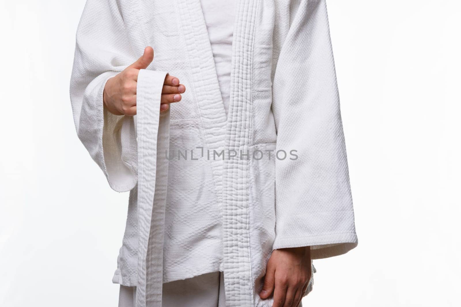 Stages of correct tying of the belt by a teenager on a sports kimono, step one