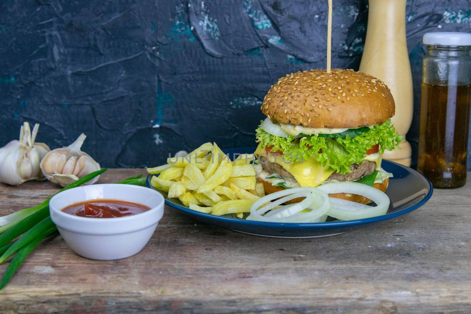Two hamburgers close-up on a round wooden board, next to, tomatoes, chopped onions and spinach leaves. Top views with clear space