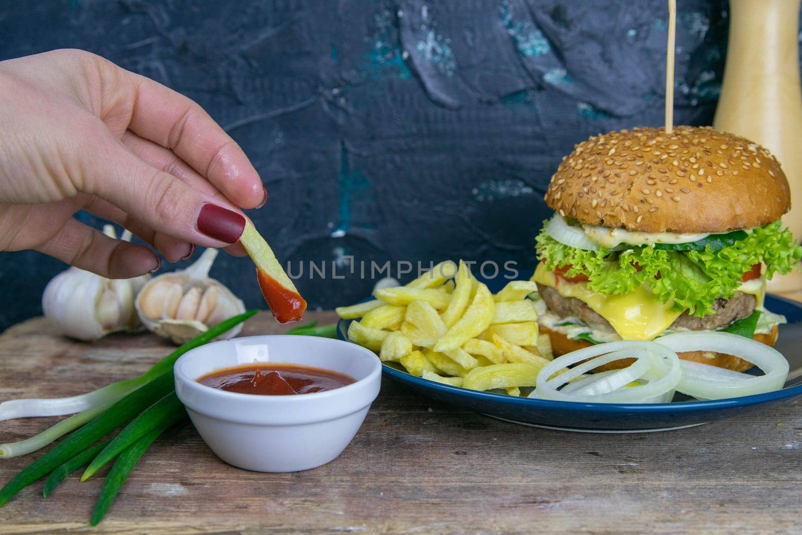 Two hamburgers close-up on a round wooden board, next to, tomatoes, chopped onions and spinach leaves. Top views with clear space