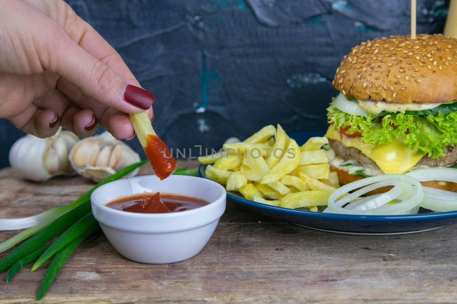 Two hamburgers close-up on a round wooden board, next to, tomatoes, chopped onions and spinach leaves. Top views with clear space