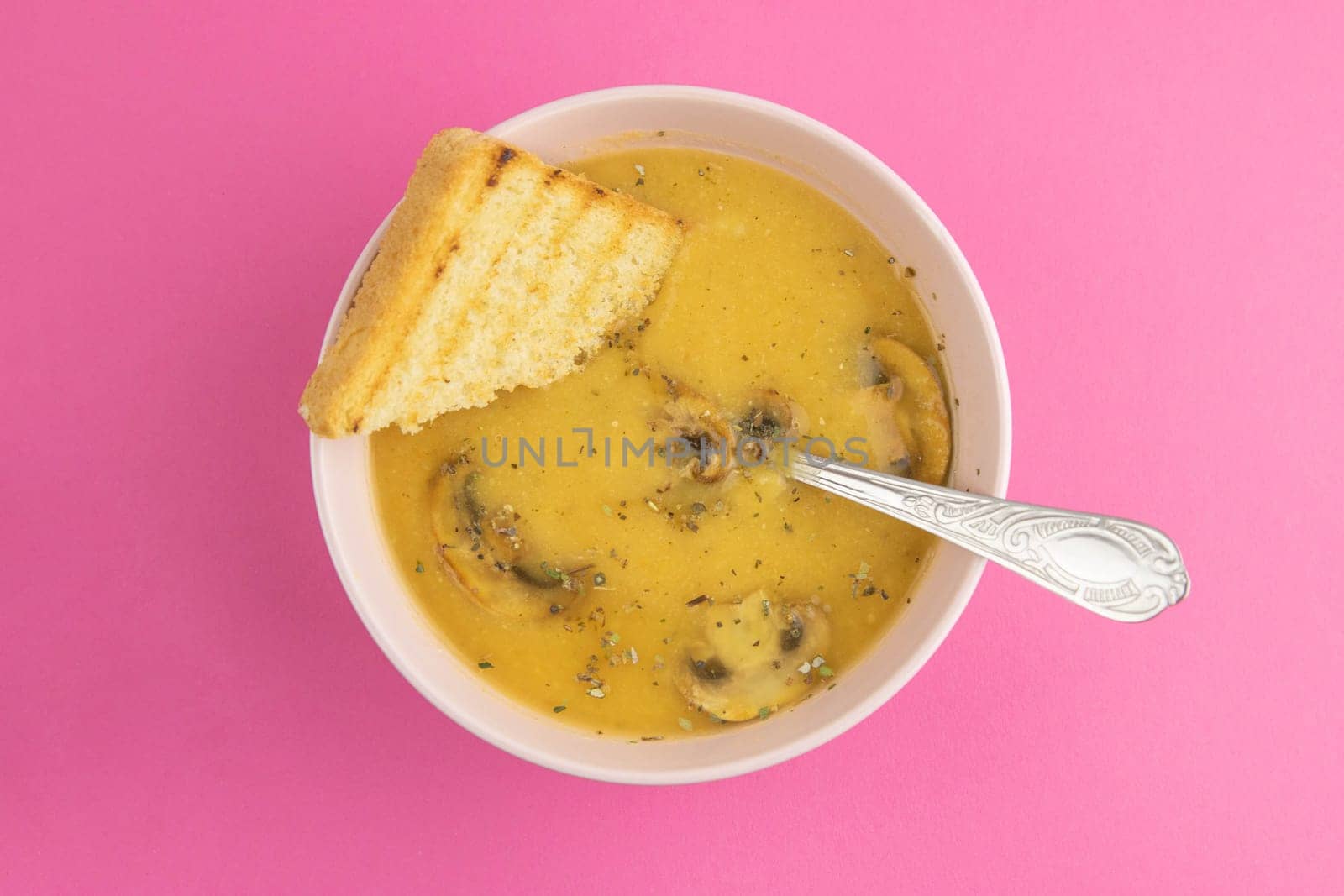 Pea soup with croutons stands on a green towel, next to there are tomatoes, toasts of pumpkin seeds, everything stands on the yellow table.