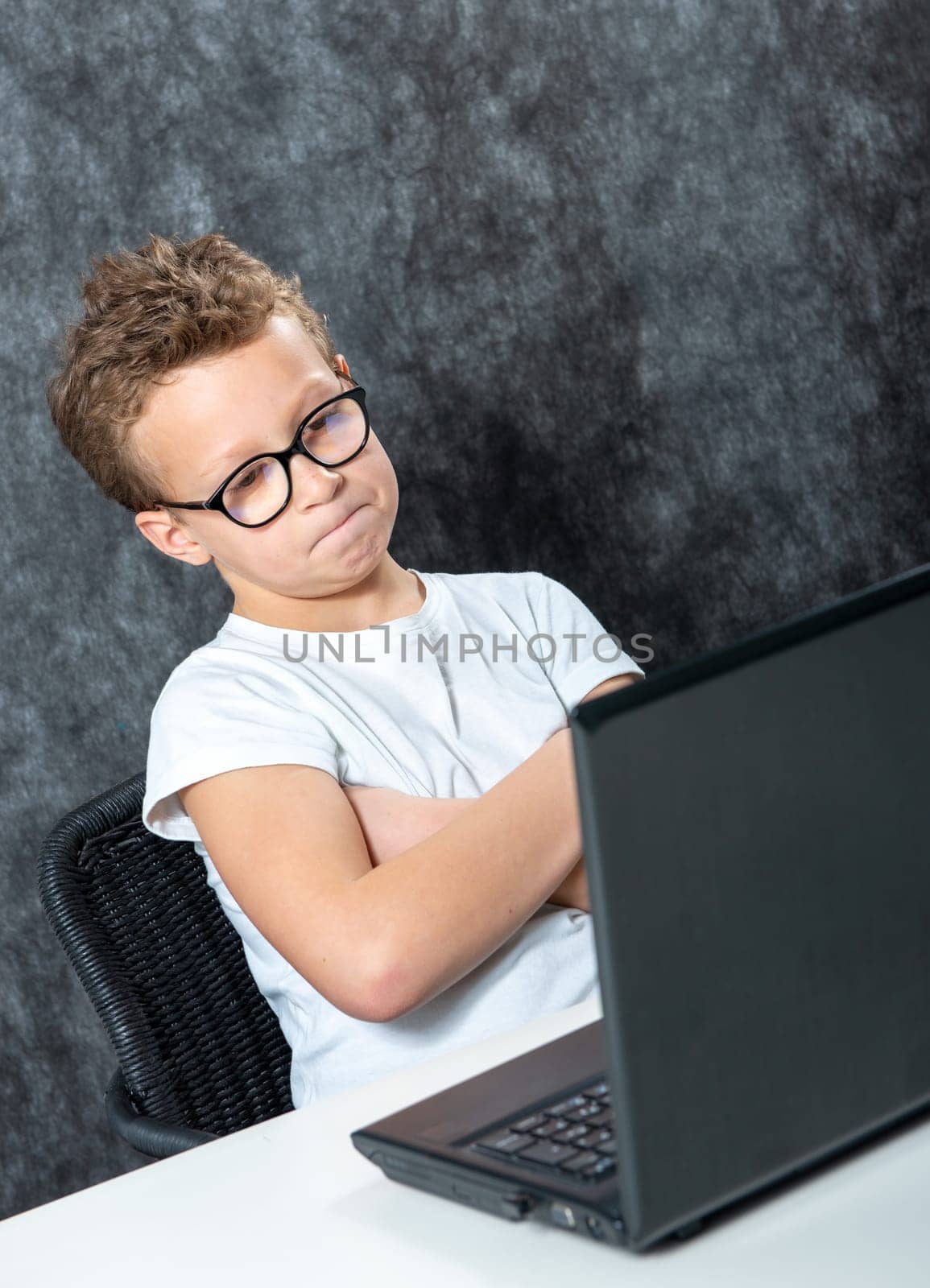 serious boy sitting with a laptop computer