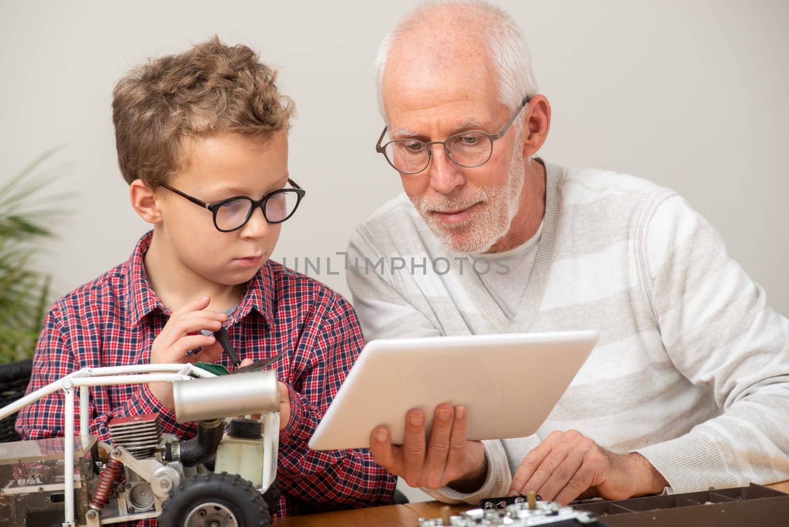grandpa and son little boy repairing a model radio-controlled car at home