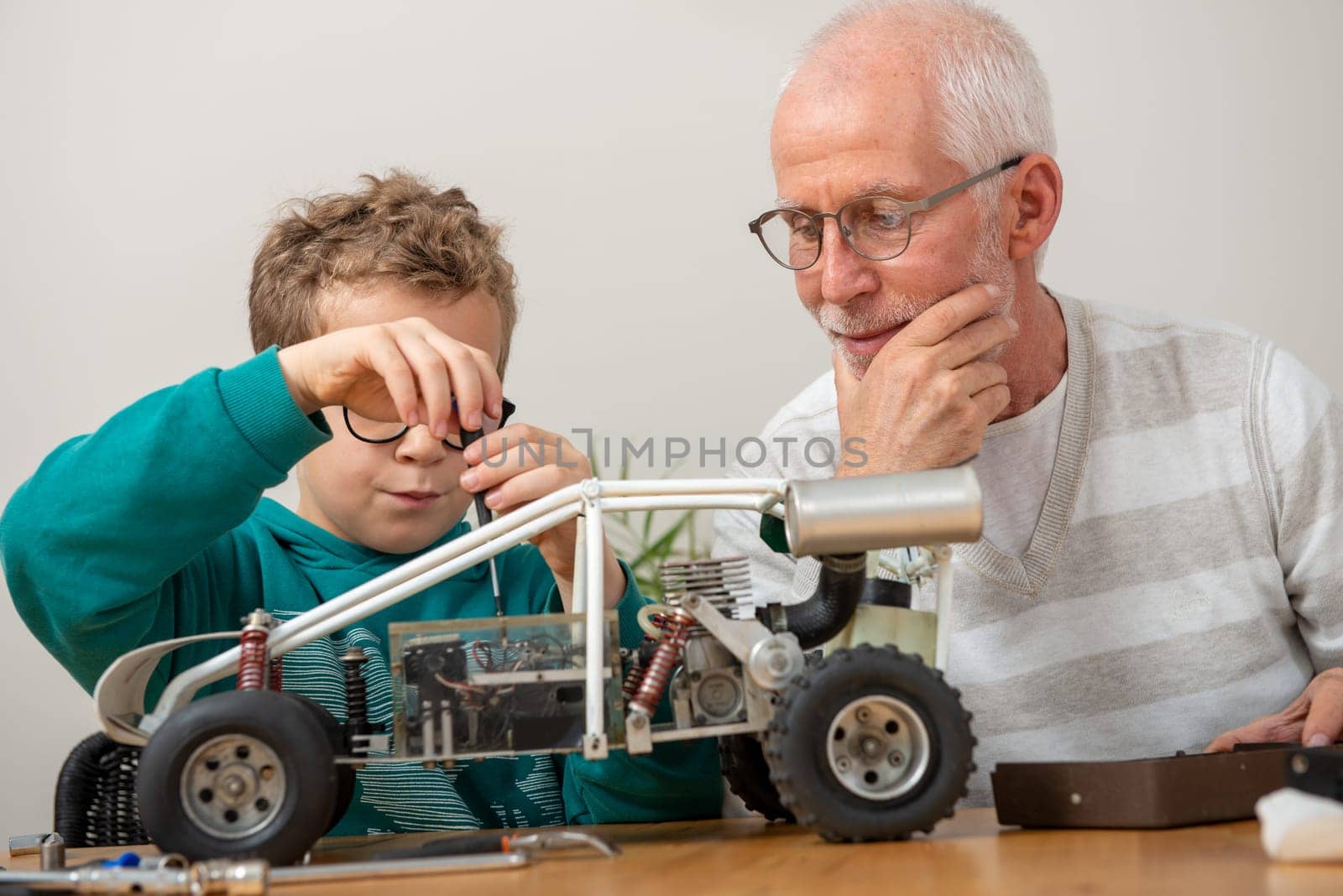 grandpa and son little boy repairing a model radio-controlled car at home