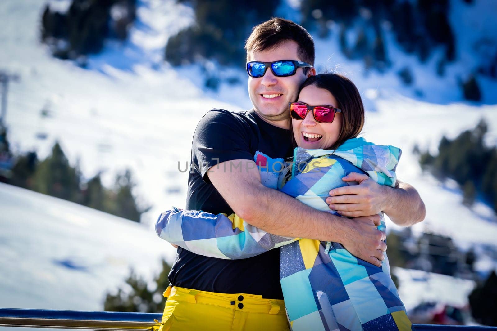 Couple, male and female, of skiers hugging and enjoying their winter holidays with winter background. El Tarter, Grandvalira, Andorra