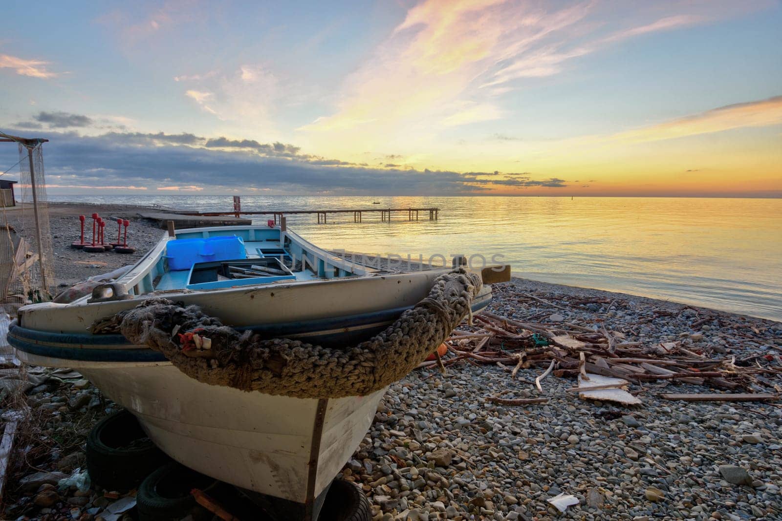 An old boat on the beach against the backdrop of a beautiful sea sunset