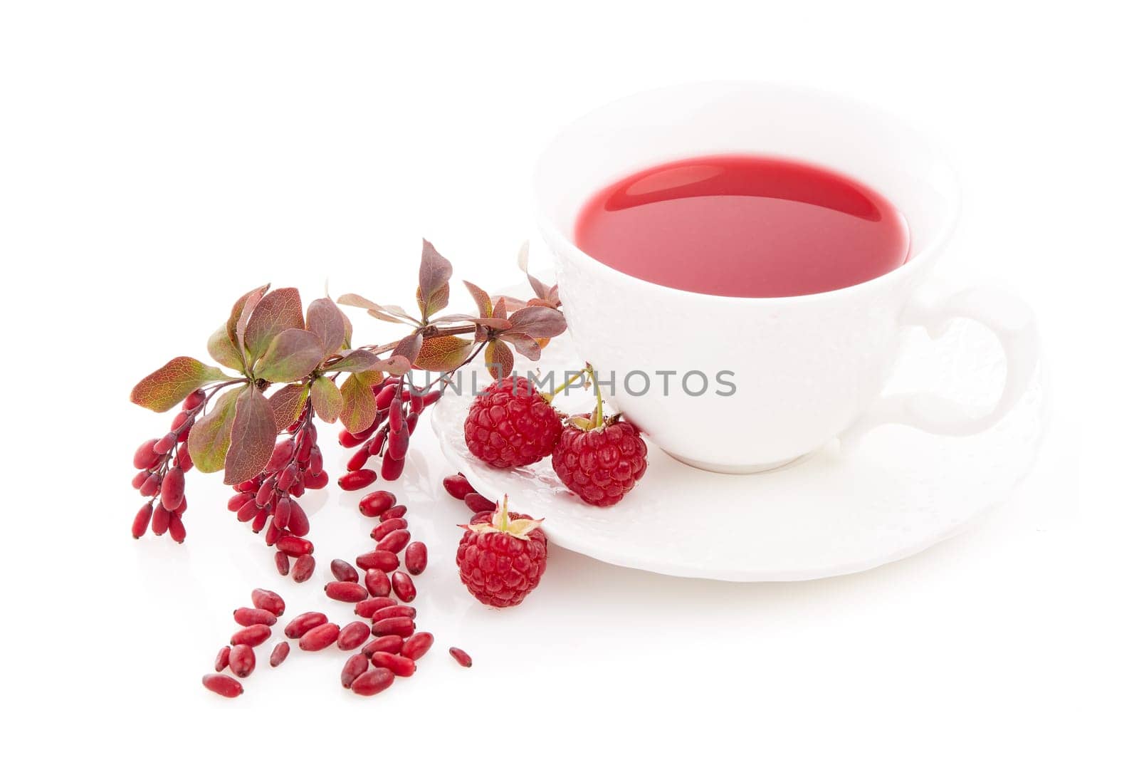Healthy fruit tea with barberries and raspberries in white cup and branch of berberry isolated on white background.