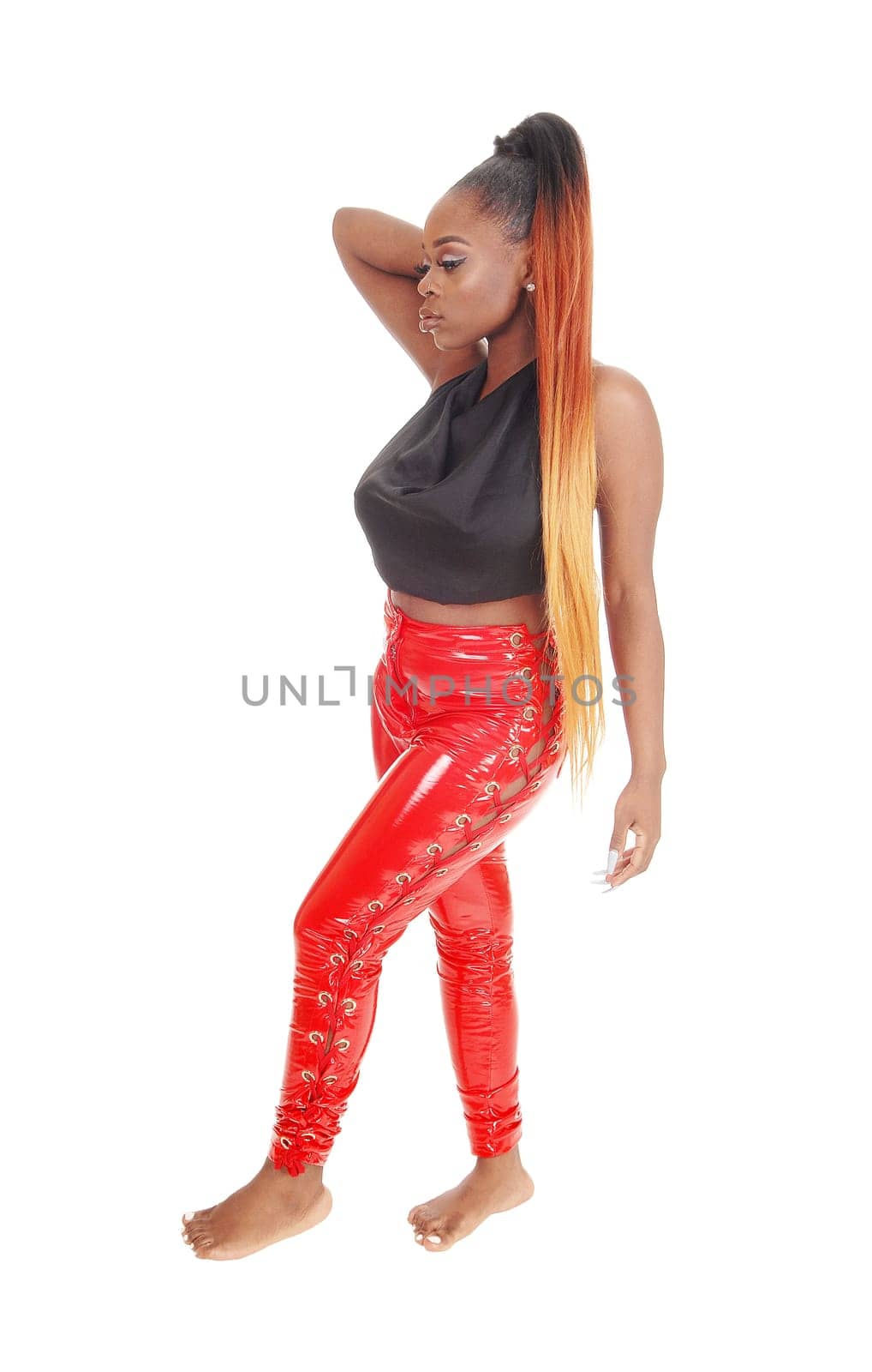 A beautiful young African American woman standing in red latex.pants and a black blouse, long hair, isolated for white background.