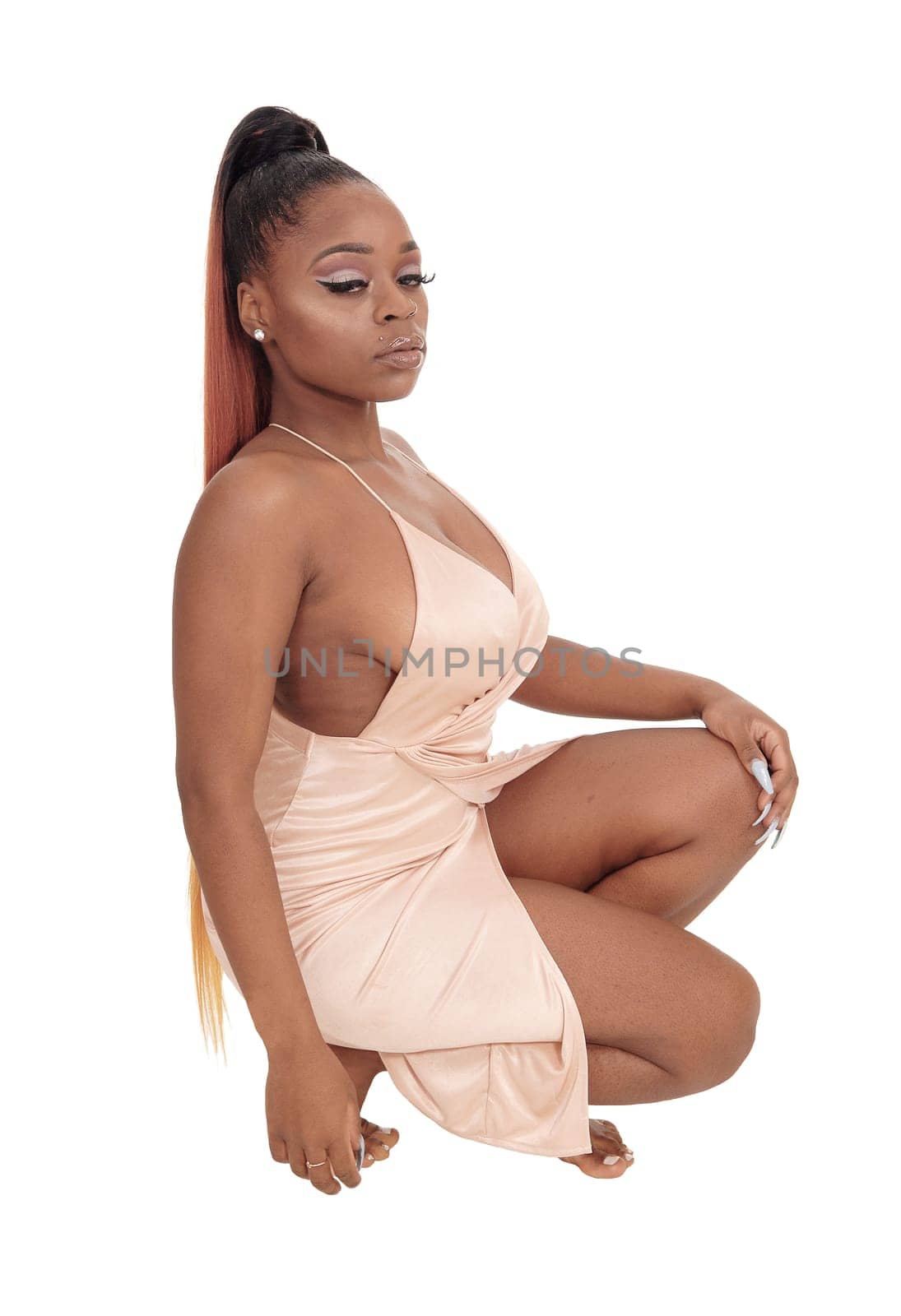 A lovely young African American woman kneeling in profile in.an pink evening gown, isolated for white background.
