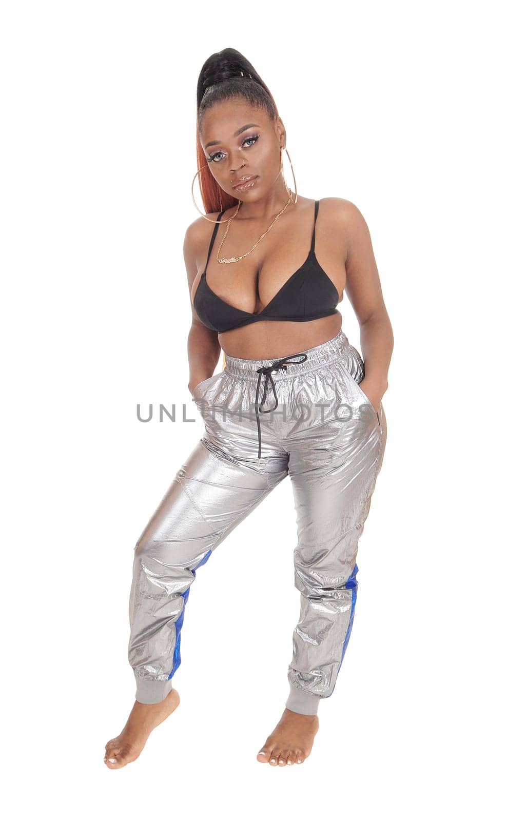 A beautiful young African American standing in the studio in silver.pants and black bra, isolated for white background.