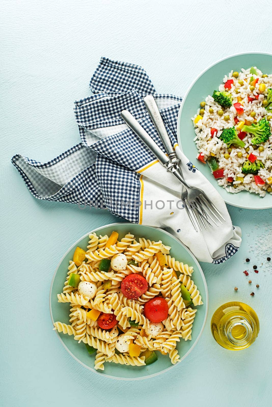 Fresh pasta salad and rice salad with mixed vegetables in a bowl on blue background. Healthy pasta and rice meals